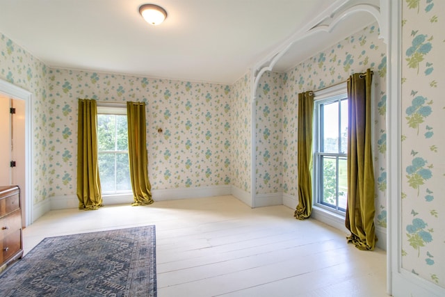 spare room featuring light wood-style floors, baseboards, and wallpapered walls