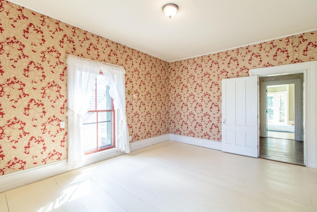 unfurnished room with wallpapered walls, light wood-style flooring, baseboards, and a wealth of natural light