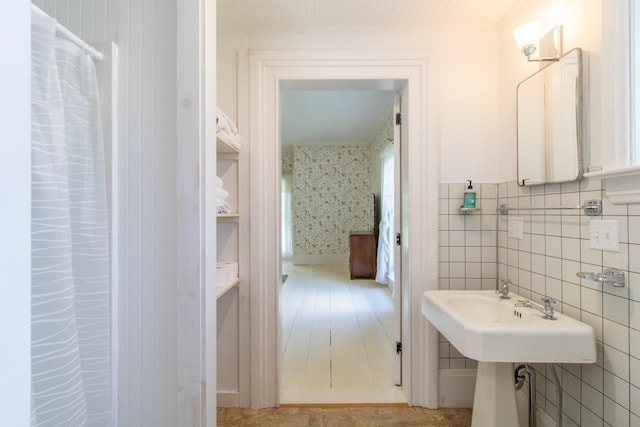 bathroom featuring tile walls and wallpapered walls