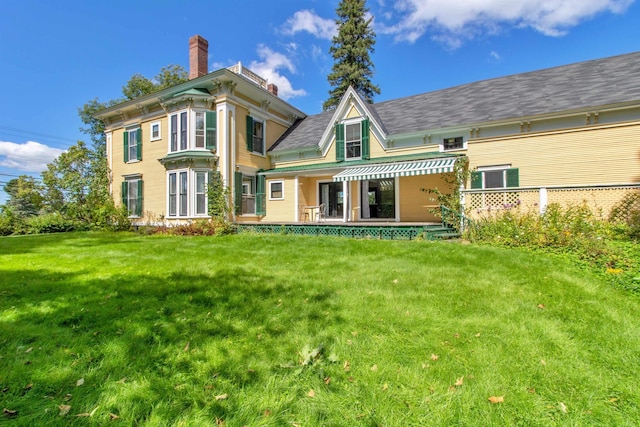 rear view of property with a lawn and a chimney