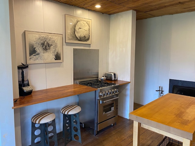 kitchen featuring a breakfast bar, wooden ceiling, dark hardwood / wood-style floors, stainless steel range, and wooden counters