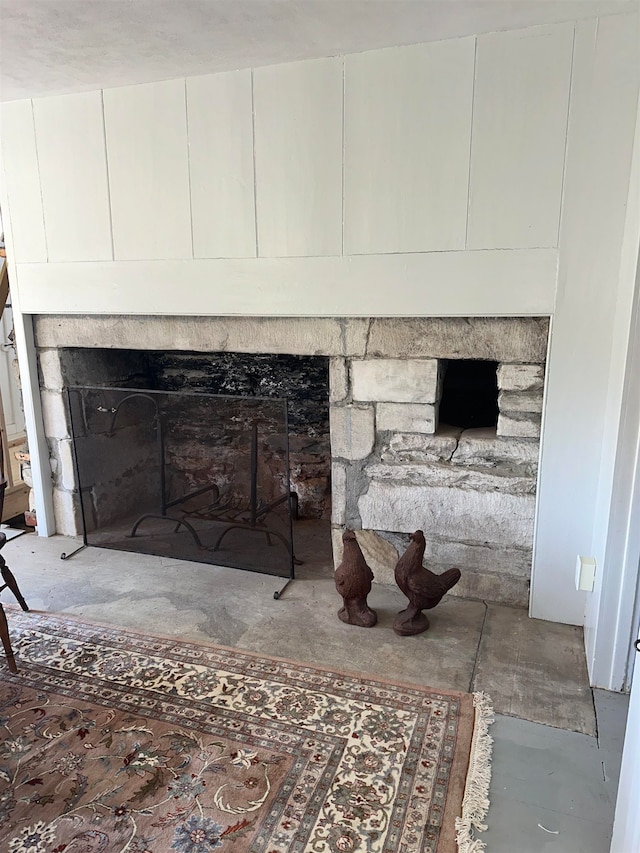 interior details featuring concrete floors and a stone fireplace