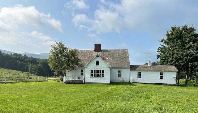 back of property with a lawn and a deck with mountain view