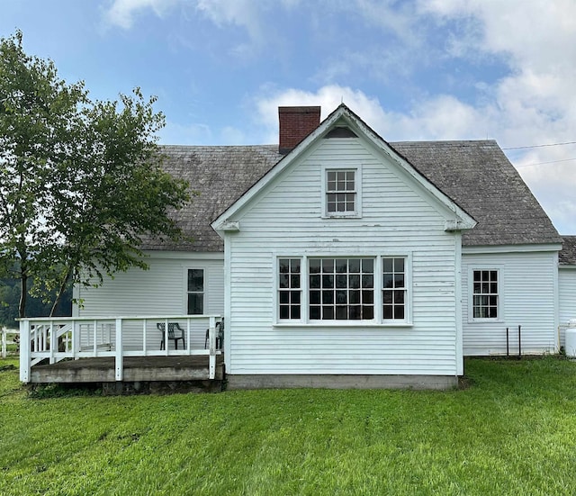 back of property featuring a deck and a lawn