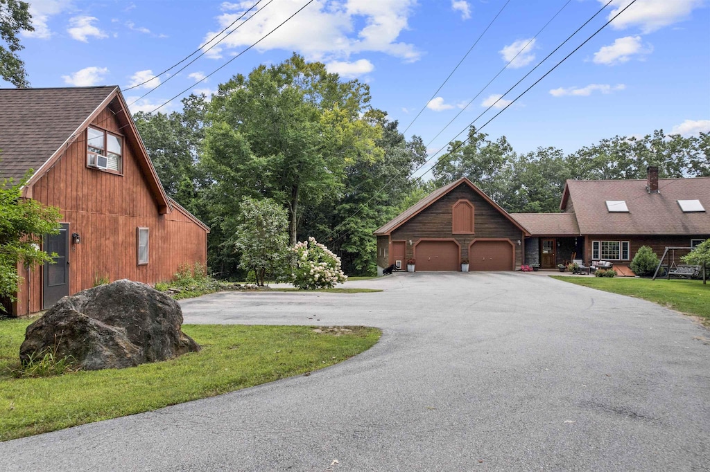 exterior space featuring a yard, roof with shingles, driveway, and an attached garage