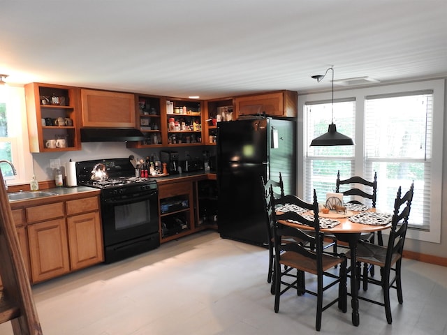 kitchen featuring decorative light fixtures, black appliances, and sink