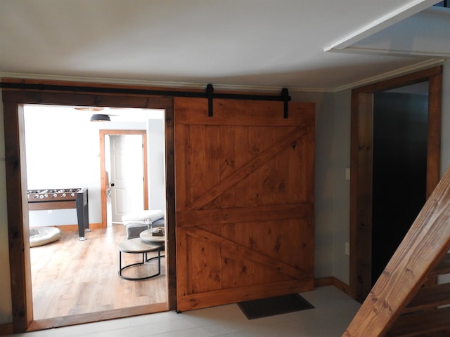 interior space with ornamental molding, a barn door, and light hardwood / wood-style floors