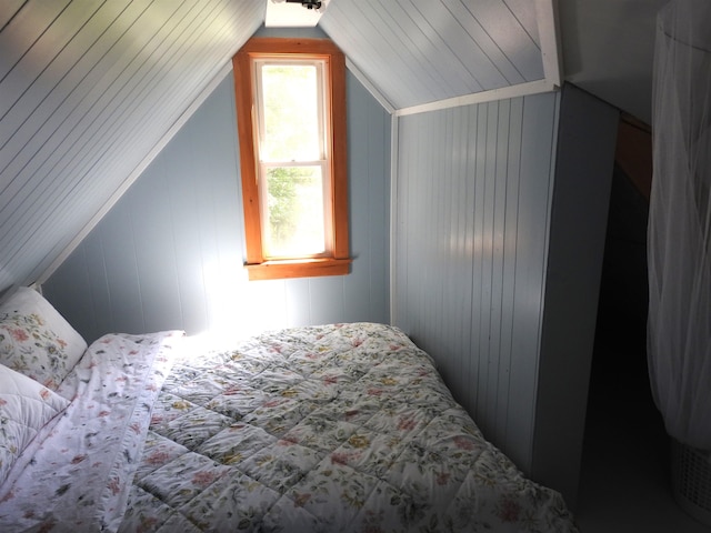 bedroom featuring lofted ceiling and wood walls