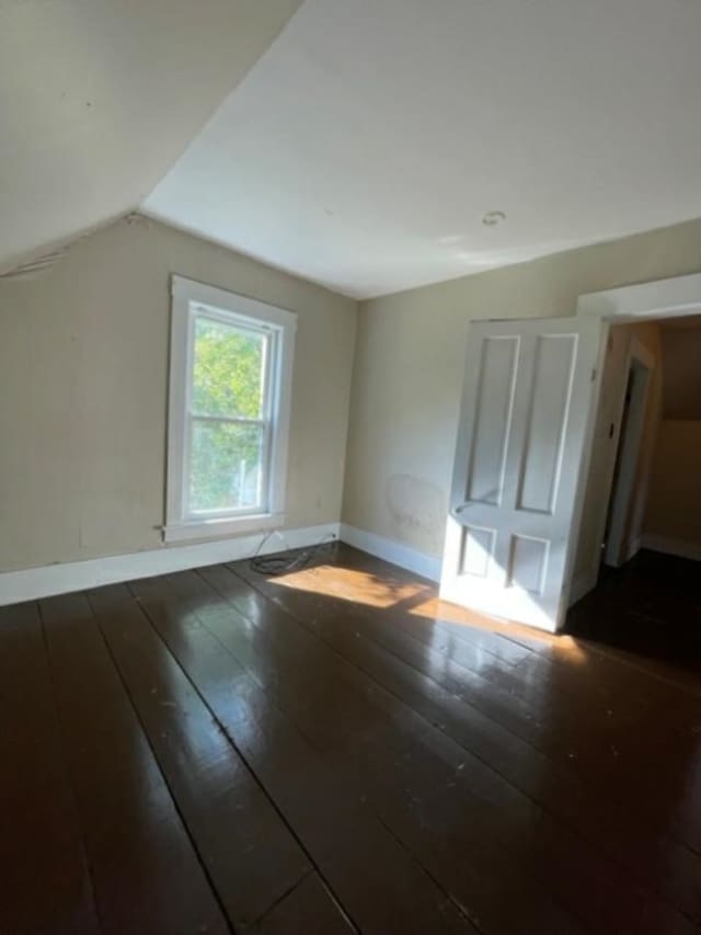 additional living space with vaulted ceiling and dark hardwood / wood-style flooring