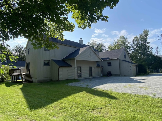 back of house featuring a yard, driveway, a chimney, and stairs