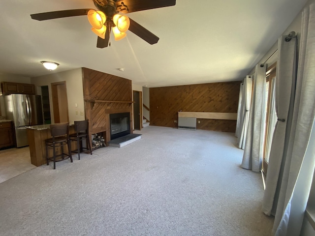 living area with light colored carpet, a fireplace, and wooden walls