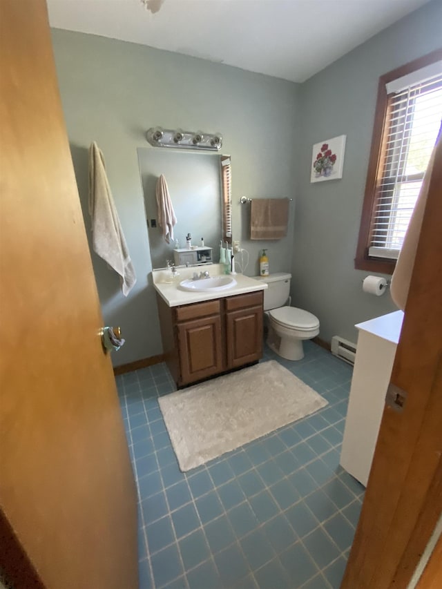 bathroom featuring baseboards, toilet, a baseboard radiator, tile patterned floors, and vanity