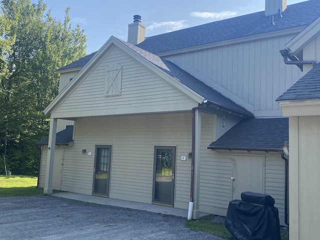 rear view of property featuring roof with shingles and a chimney