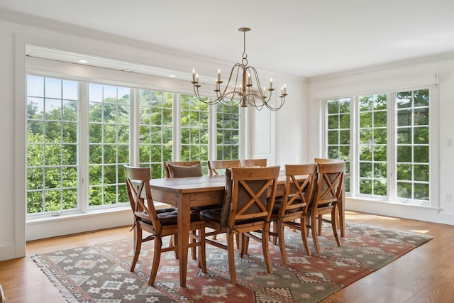 dining area with light wood-type flooring, ornamental molding, and a chandelier