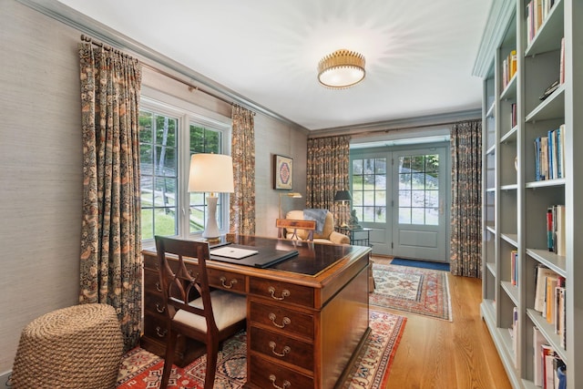 office with light wood-type flooring, crown molding, and a healthy amount of sunlight