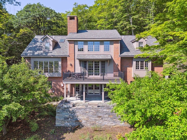 rear view of house with a wooden deck and a patio