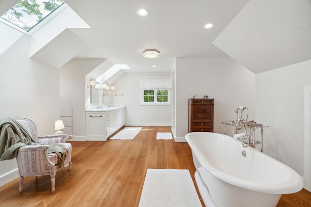 bathroom with vanity, an inviting chandelier, a skylight, a tub to relax in, and wood-type flooring