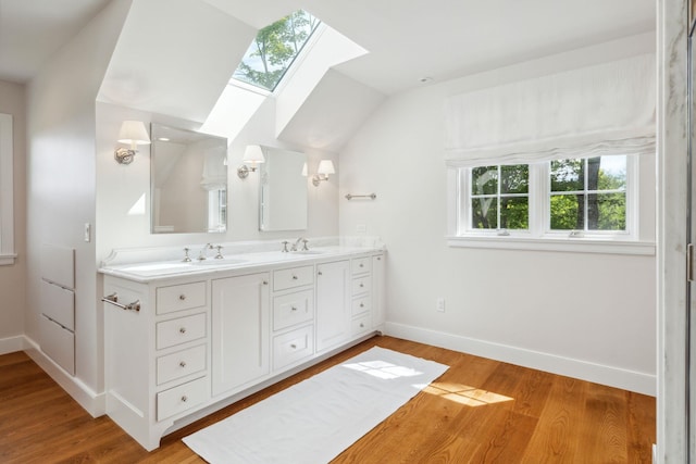 bathroom with hardwood / wood-style flooring, vanity, and lofted ceiling with skylight