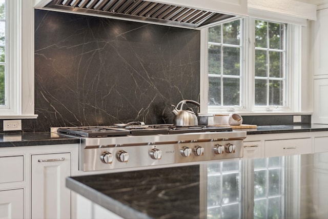 interior space featuring tasteful backsplash, white cabinets, extractor fan, and stainless steel gas stovetop