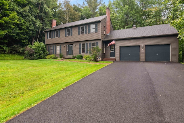 colonial house featuring a garage and a front lawn