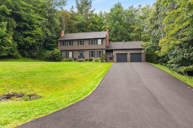 colonial house featuring a garage and a front lawn