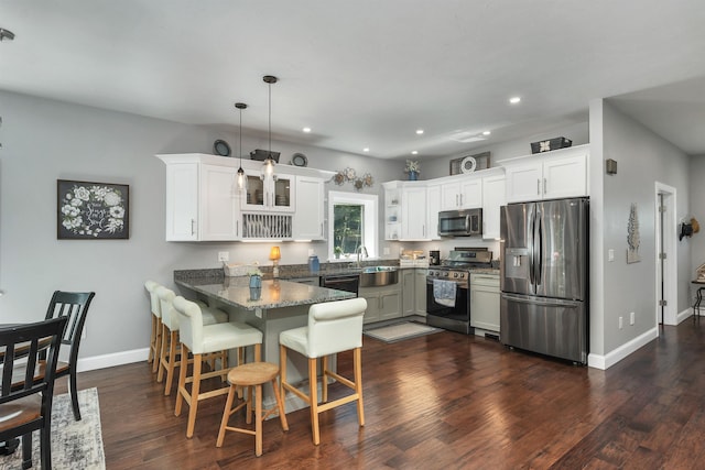 kitchen featuring white cabinets, kitchen peninsula, appliances with stainless steel finishes, and hanging light fixtures