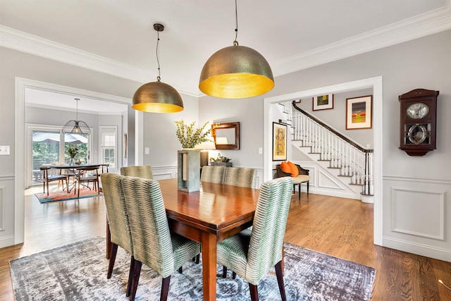 dining room with stairway, wood finished floors, and ornamental molding