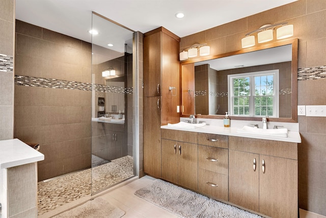 full bath with a sink, tile walls, double vanity, and a walk in shower