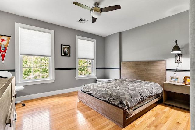 bedroom featuring visible vents, ceiling fan, baseboards, and wood-type flooring