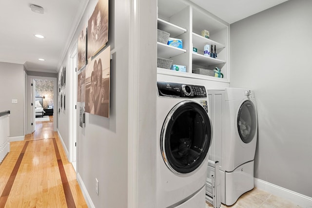 clothes washing area with baseboards, washing machine and dryer, laundry area, and crown molding