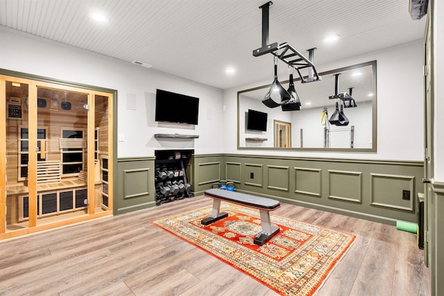 living area with recessed lighting, visible vents, light wood-style flooring, and a wainscoted wall