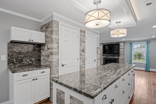 kitchen featuring a fireplace, dark hardwood / wood-style flooring, decorative light fixtures, and white cabinets