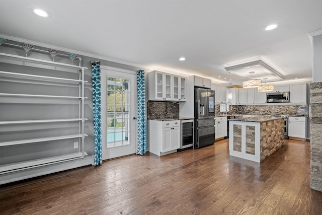 kitchen with a kitchen island, dark hardwood / wood-style floors, tasteful backsplash, stainless steel appliances, and white cabinetry