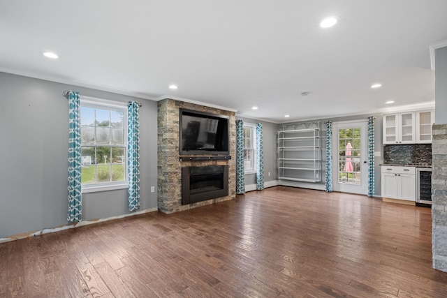 unfurnished living room with beverage cooler, wood-type flooring, a fireplace, and crown molding