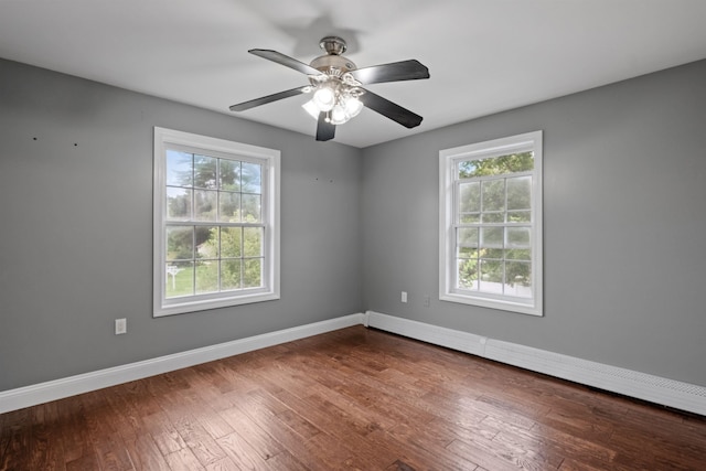 empty room featuring dark wood-type flooring, ceiling fan, a baseboard radiator, and a healthy amount of sunlight