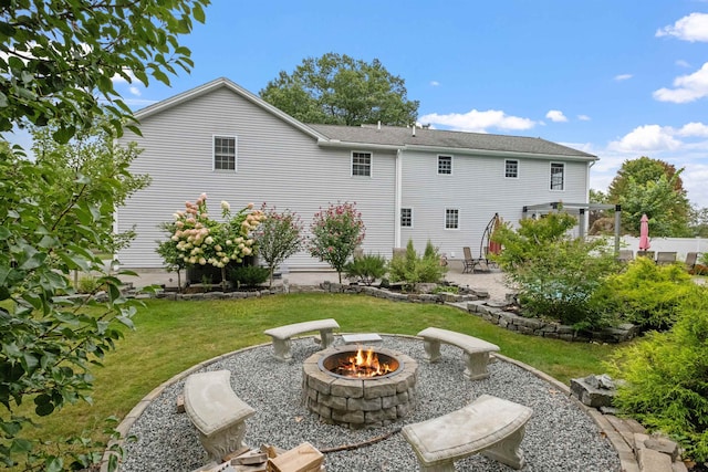 rear view of property with a fire pit, a yard, and a patio area