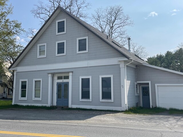 view of front facade featuring french doors, an attached garage, and a shingled roof