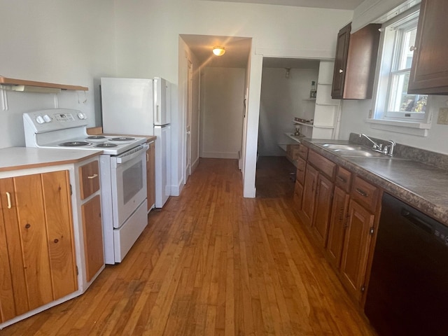 kitchen featuring light wood finished floors, electric range, dishwasher, dark countertops, and a sink