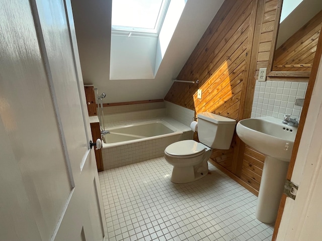 bathroom with tiled tub, toilet, decorative backsplash, and tile patterned flooring