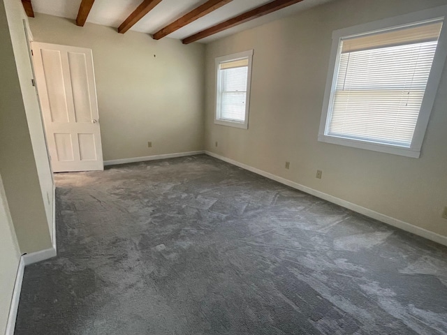 carpeted empty room with beamed ceiling