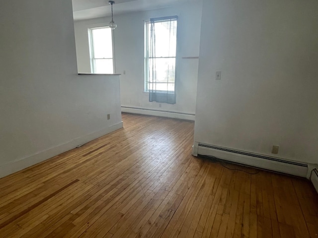 spare room with a baseboard radiator, baseboards, and hardwood / wood-style floors