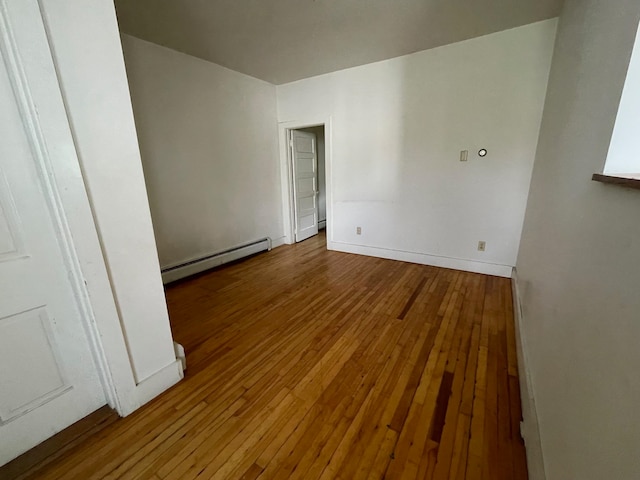 empty room featuring a baseboard heating unit and hardwood / wood-style floors