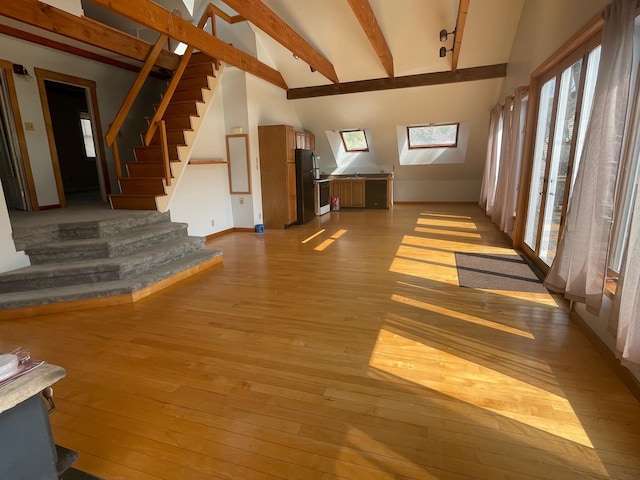 unfurnished living room with high vaulted ceiling, beam ceiling, and light hardwood / wood-style flooring