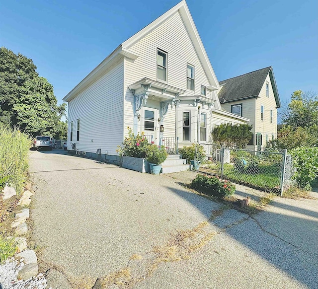 view of front facade featuring fence and aphalt driveway