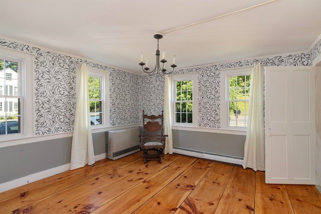 unfurnished room with a baseboard radiator, a wealth of natural light, and light hardwood / wood-style flooring