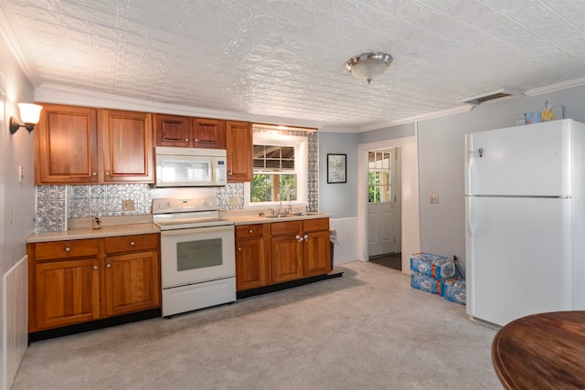 kitchen with white appliances, backsplash, crown molding, and sink