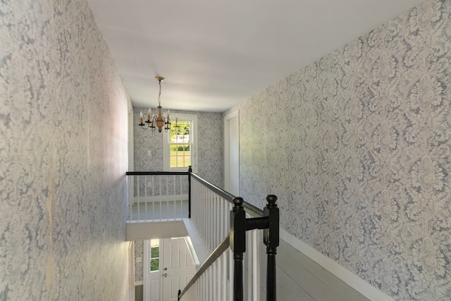 stairway with wood-type flooring, a notable chandelier, and a healthy amount of sunlight