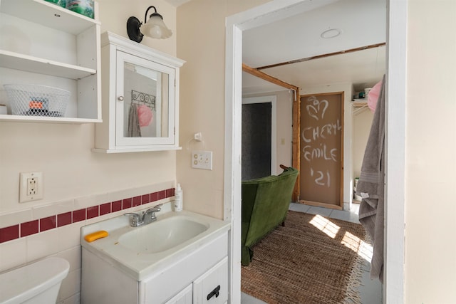 bathroom with vanity, toilet, and tile walls