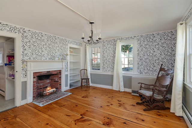 interior space with a chandelier, hardwood / wood-style flooring, a brick fireplace, and a baseboard radiator