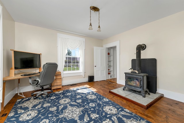 office featuring wood-type flooring and a wood stove